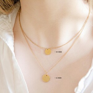 Puede incluir: Dos collares de oro con colgantes redondos. El collar superior tiene un colgante de 10 mm y el collar inferior tiene un colgante de 12 mm.