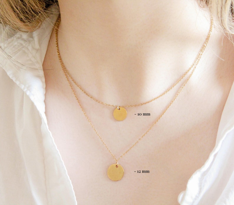 Puede incluir: Dos collares de oro con colgantes redondos. El collar superior tiene un colgante de 10 mm y el collar inferior tiene un colgante de 12 mm.