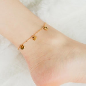 May include: A gold anklet with a delicate chain and small round charms.
