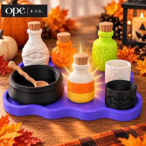 May include: A Halloween-themed set featuring a black cauldron with a wooden spoon, a white mummy bottle, an orange pumpkin bottle, a green potion bottle, a candy corn bottle, a white ghost cup, and a black bat cup on a purple wavy tray.