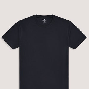 Puede incluir: Una camiseta de manga corta azul marino con una etiqueta blanca que dice "Brian Cox" y "Essential".