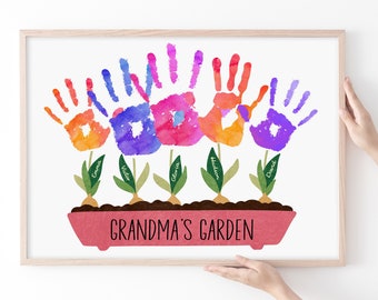 May include: A framed watercolor print featuring a garden scene. Colorful handprints in shades of orange, blue, pink, and purple form the flowers. Each flower has a name on its stem. The words "Grandma's Garden" are written at the bottom.