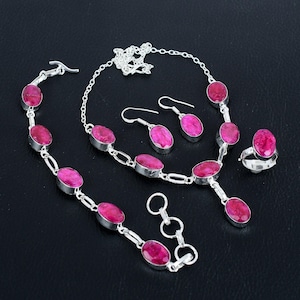 Op de afbeelding: Een zilveren sieradenset met roze ovale edelstenen. De set bevat een ketting, armband, oorbellen en een ring.