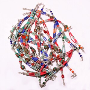 Puede incluir: Un montón de pulseras de cuentas de colores con detalles plateados. Las pulseras están hechas con cuentas turquesa, rojas, azules y blancas.