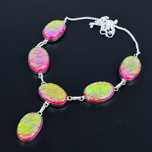Puede incluir: Un collar de plata con piedras ovaladas e iridiscentes en tonos rosa y verde. Las piedras est&aacute;n engastadas en plata y unidas por eslabones de plata. El collar tiene una cadena fina.