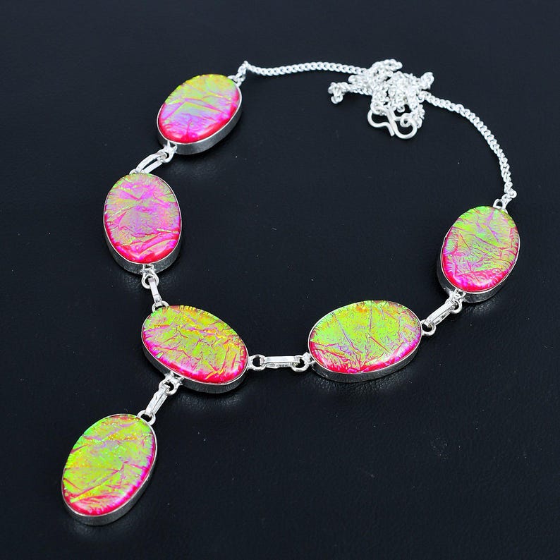 Puede incluir: Un collar de plata con piedras ovaladas iridiscentes en tonos rosa y verde. Las piedras est&aacute;n engastadas en biseles de plata y unidas por eslabones de plata. El collar tiene una cadena fina.