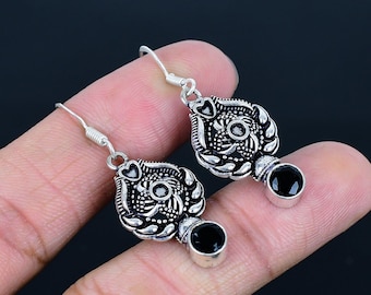 Puede incluir: Pendientes de plata con detalles de piedras preciosas negras. Los pendientes tienen diseños florales intrincados y una forma de lágrima.