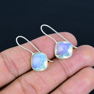 May include: A pair of silver dangle earrings with iridescent blue and purple gemstone drops.