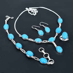 Könnte beinhalten: Ein silbernes Halsketten-, Armband- und Ohrring-Set mit ovalen türkisfarbenen Steinen. Das Set enthält auch einen Ring mit einem türkisfarbenen Stein.