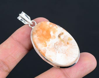 May include: A silver pendant featuring a white and orange oval-shaped gemstone with a detailed, organic pattern. The pendant has a silver bail for attaching to a chain.