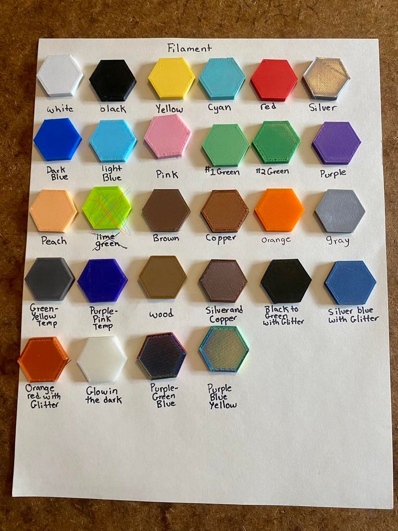May include: A chart showing different colors of filament for 3D printing. The colors include white, black, yellow, cyan, red, silver, dark blue, light blue, pink, green, peach, brown, copper, orange, gray, purple, wood, silver and copper, black to green with glitter, silver blue with glitter, orange red with glitter, glow in the dark, purple green blue, and purple blue yellow.