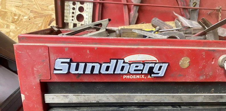 May include: A red metal toolbox with a silver metal nameplate that reads "Sundberg Phoenix, AZ".