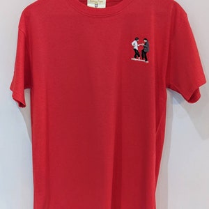 May include: Red short-sleeved t-shirt with an embroidered image of two people dancing. The t-shirt has a small tag on the front that says "Lemon Type".