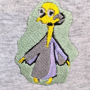 May include: Embroidered patch of a cartoon character with a yellow head, gray body, and purple sleeves. The character is wearing a robe and has a green background.