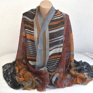 May include: A multi-coloured scarf with a striped pattern and floral designs. The scarf is made of a soft, lightweight fabric and is perfect for adding a touch of style to any outfit.