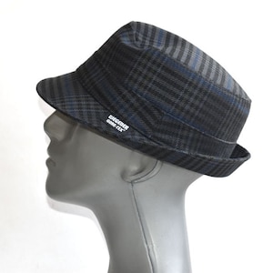 Może przedstawiać: Czarno-niebieski kapelusz fedora w kratę z czarną i białą etykietą "UGG Australia Gore-Tex".