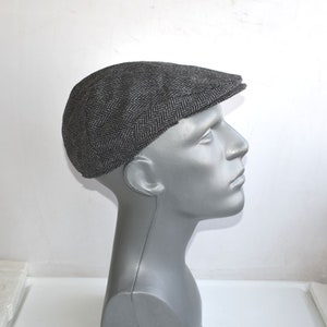 May include: A grey tweed flat cap with a herringbone pattern.