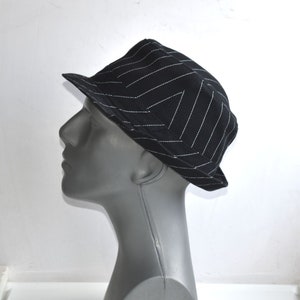 May include: A black and white striped fedora hat. The hat is made of a soft, textured fabric.
