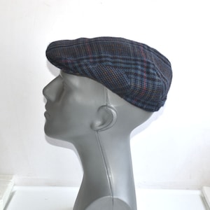 May include: A blue, black and brown plaid newsboy cap. The cap is made of a soft, textured fabric.