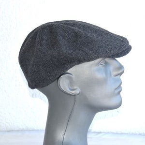 May include: A grey wool flat cap with a slightly curved brim.