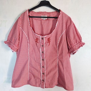 May include: Red and white gingham button-up shirt with white lace trim and red embroidered flowers. The shirt has short sleeves with ruffles at the cuffs.