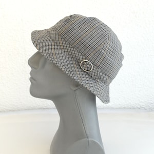 May include: A gray and beige plaid bucket hat with a silver ring accent.