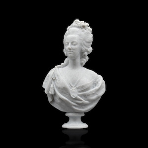 May include: A white marble-textured bust sculpture depicting a person with an elaborate, high-piled hairstyle adorned with floral details. The figure wears a draped garment with a tassel accent and a central oval pendant hanging from a necklace.