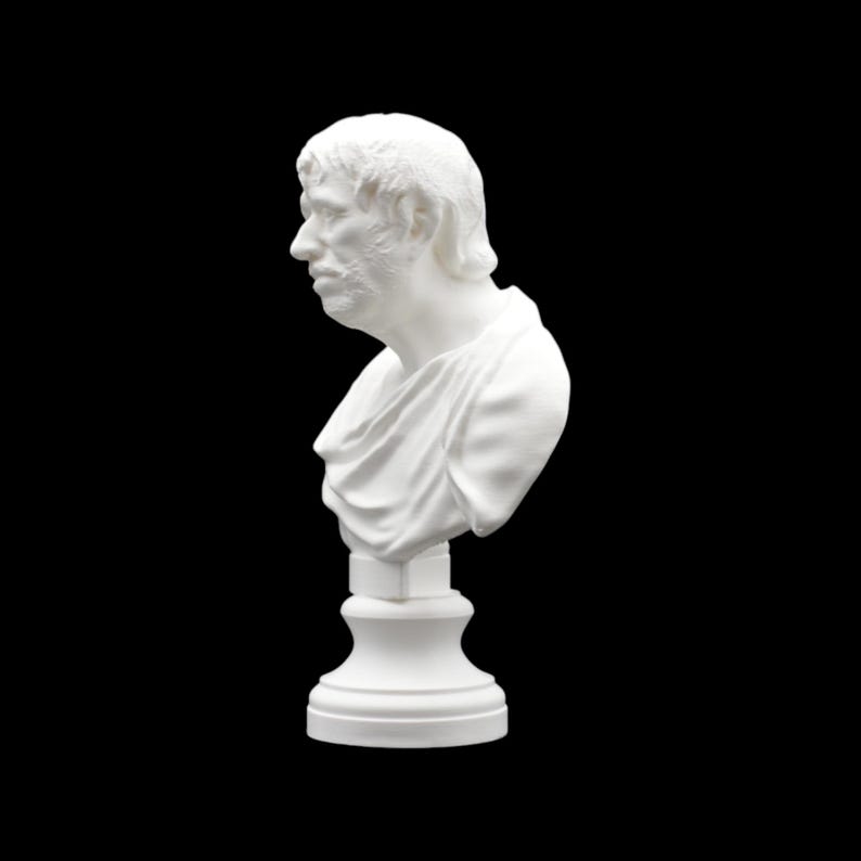 May include: A white bust sculpture of a man in profile, featuring detailed facial features and draped clothing. The sculpture is mounted on a pedestal, all against a black background. The bust appears to be made of a solid material.