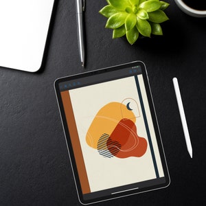 May include: A digital tablet displaying a minimalist design with abstract shapes in shades of orange, red, and brown. The design features a crescent moon and a black and white striped pattern. The text "Stardust Lovers" is displayed at the bottom of the screen.