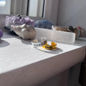 May include: Two silver rings with the words "POGUES" and "KOOKS" engraved on them.