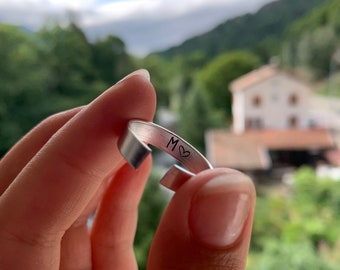 May include: A silver ring with the letter "M" and a heart engraved on it.