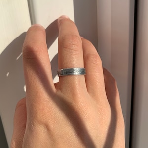 Puede incluir: Un anillo de banda de plata con un acabado texturizado.