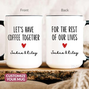 May include: Two white coffee mugs with black handles. The front mug says "Let's have coffee together" with a red heart and the names "Joshua & Riley". The back mug says "For the rest of our lives" with a red heart and the names "Joshua & Riley".
