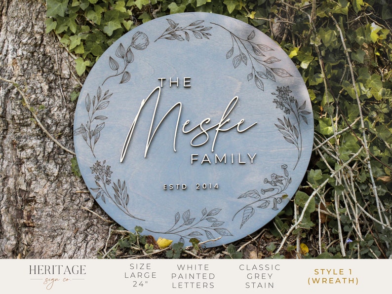 May include: A light blue round wooden sign with a floral wreath design. The sign says "The Meske Family Est. 2014".