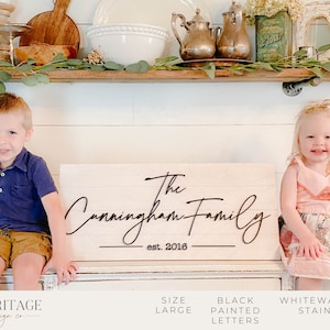 May include: A whitewash stained wooden sign with the text "The Cunningham Family est. 2016" in black painted script lettering.