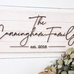 May include: White wooden sign with black cursive lettering that reads "The Cunningham Family est. 2016".