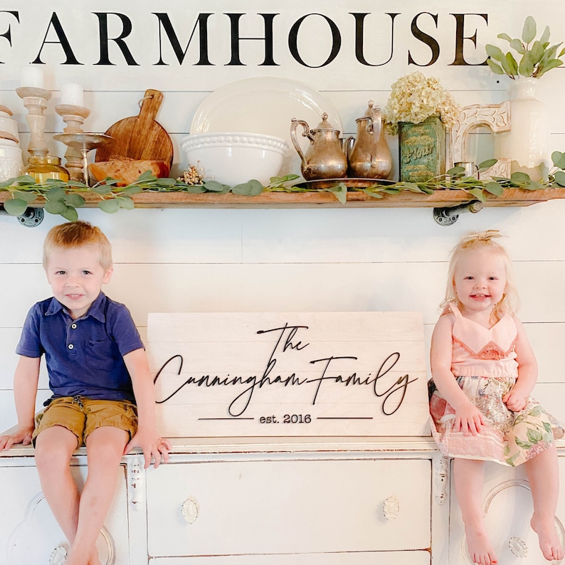 Farmhouse decor black and white sign with family last name sign in farmhouse kitchen