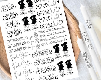 May include: A sheet of white sticker paper with black ink designs. The stickers feature Easter greetings in German, including "Frohe Ostern" (Happy Easter), "Osterlicht" (Easter light), "Osterfreuer to go" (Easter joy to go), and "kleiner Ostergrub" (small Easter greeting).