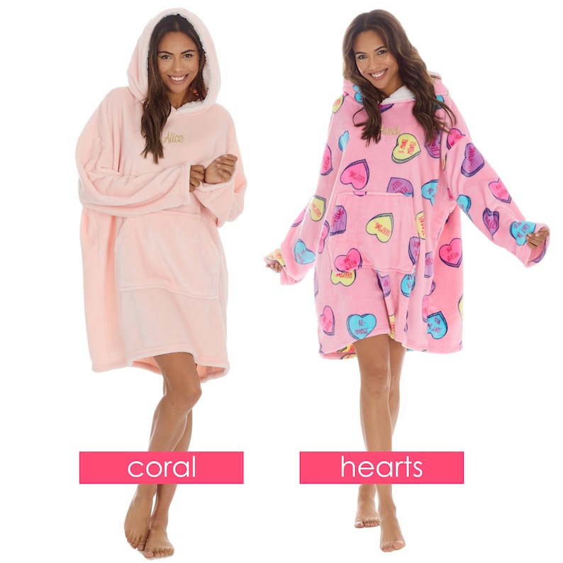 May include: Two pink oversized hooded blankets. One is solid pink with the name "Alice" embroidered on the front. The other is pink with a pattern of colourful candy hearts. The blankets are called "coral" and "hearts".
