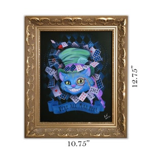 Op de afbeelding: Een ingelijst schilderij van de Cheshire Cat uit Alice in Wonderland. De kat is blauw met een groene hoed en een ondeugende grijns. De achtergrond is zwart met een schaakbordpatroon en speelkaarten. De tekst "We're all mad here" staat op een banner onder de kat. De lijst is goudkleurig met sierlijke details. Het schilderij is 10,75 inch breed en 12,75 inch hoog.