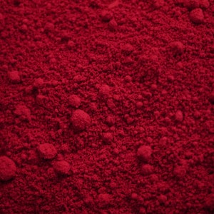May include: Close-up of a deep red powder, possibly a pigment or food coloring. The powder has a fine, granular texture.