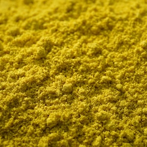 May include: Close-up of a pile of bright yellow turmeric powder.
