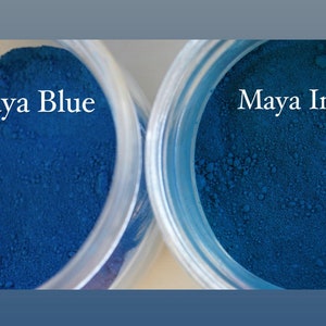 May include: Two small jars of blue pigment powder. The jar on the left is labeled "Maya Blue" and the jar on the right is labeled "Maya Indigo".