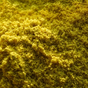 May include: Close-up of a yellow powder, possibly turmeric or curry powder, with a grainy texture.