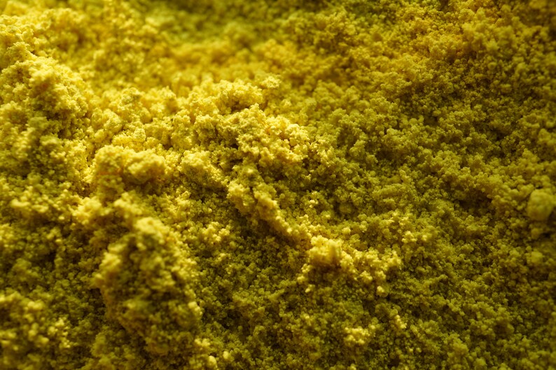 May include: Close-up of a yellow powder, possibly turmeric or curry powder, with a grainy texture.