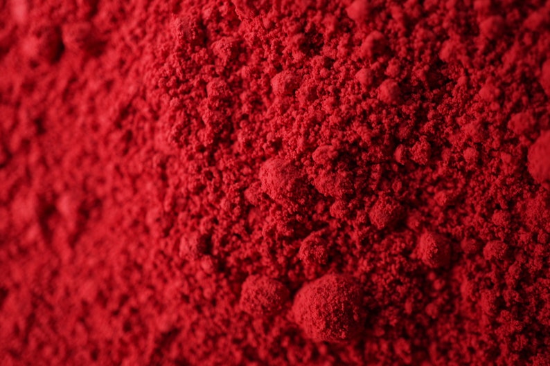 May include: Close-up of a pile of bright red powder. The powder has a fine, granular texture.