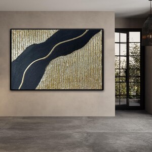 May include: Abstract painting with a black and gold color scheme. The painting features a black, wavy line on a gold background with a textured surface.