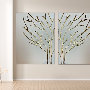 May include: Two abstract wall art pieces featuring a gold metallic tree branch design on a white background.