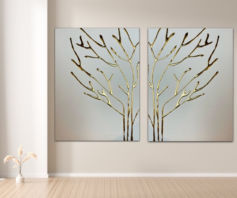 May include: Two abstract wall art pieces featuring a gold metallic tree branch design on a white background.
