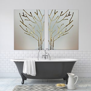 May include: A black freestanding bathtub with a white towel draped over the side. Two gold framed paintings of stylized trees hang above the tub. The paintings are on a white tiled wall.